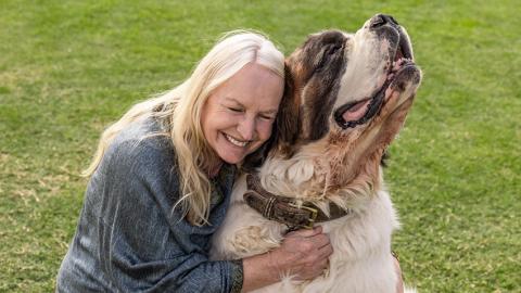 Woman with blonde hair hugging a Saint Bernard dog