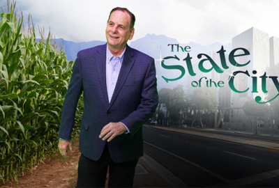 Mayor Hartke stands between a cornfield and Chandler City Hall with the text "The State of the City"