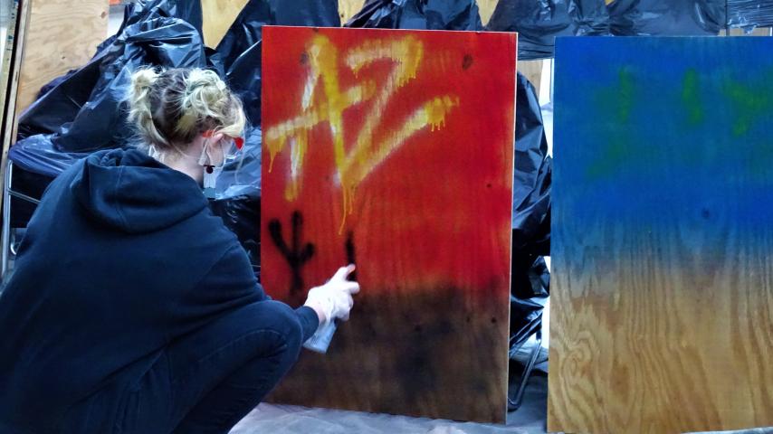 Teen graffiti painting on plywood as part of the Graffiti Painted Positive Program