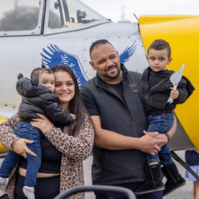 a family posing in front of a yellow aircraft