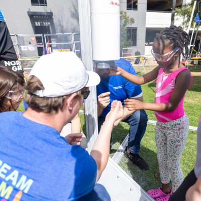 Northrop Grumman employee helps a young girl prepare for a rocket launch