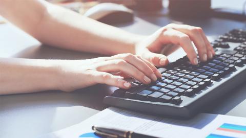 Hands typing on a computer keyboard