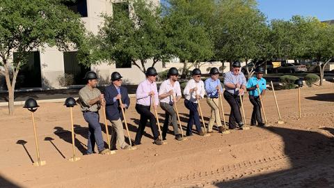 Laser Components Management shoveling dirt at groundbreaking event