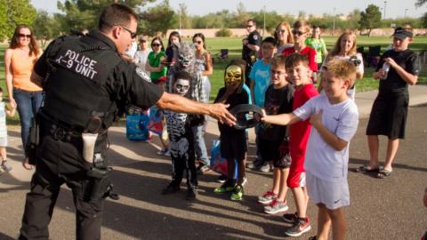 Chandler Police officer handing an item to a kid